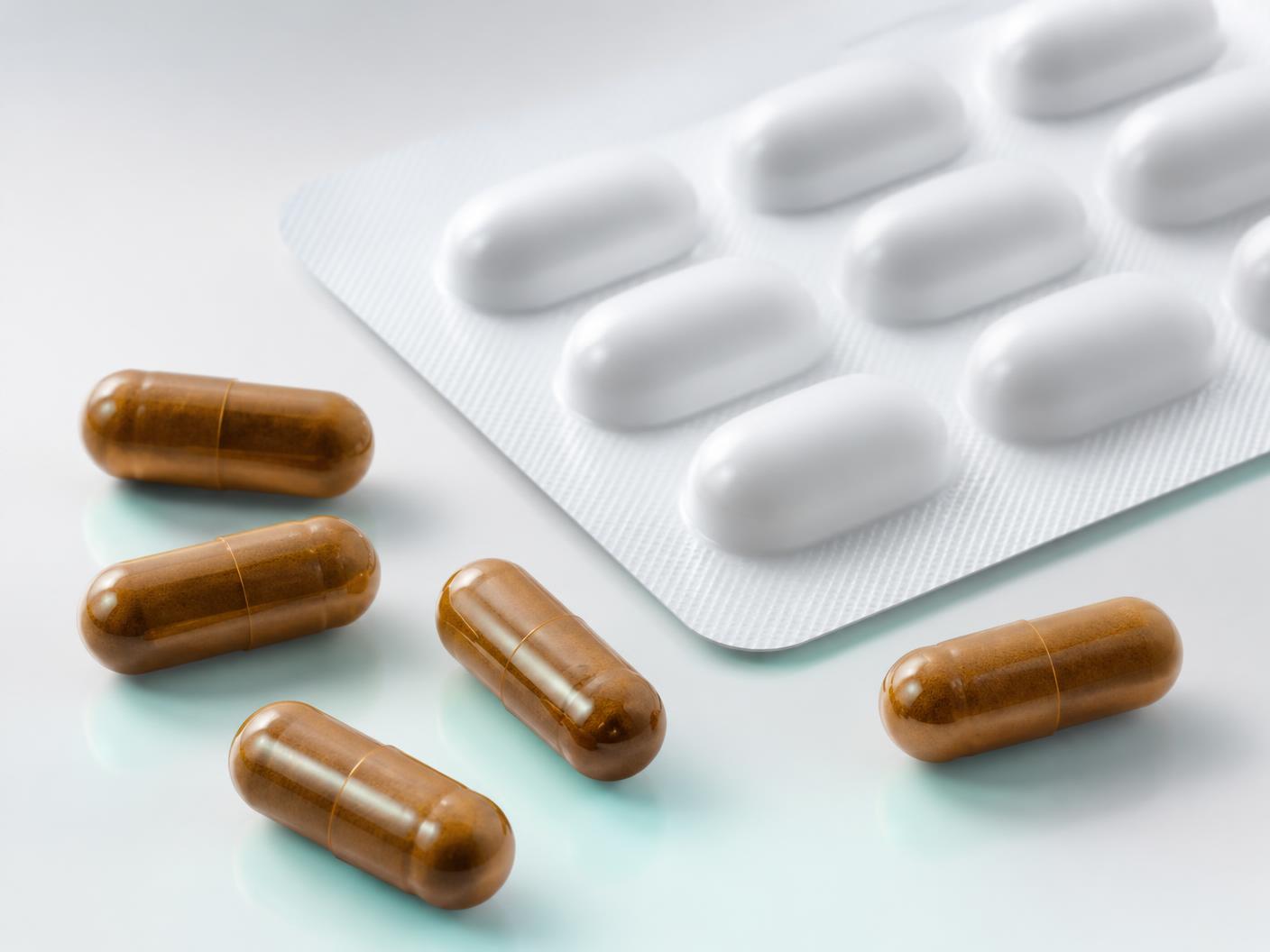Cápsulas de medicamento importado sobre superfície clara